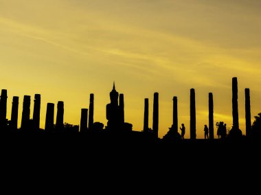 Sukhothai Tarih Parkı 'ndaki Wat Mahathat Tapınağı' nın siluetinin inanılmaz manzarası. Altından günbatımı arka planında büyük bir Buda heykeli Tayland 'daki UNESCO Dünya Mirası Alanı..