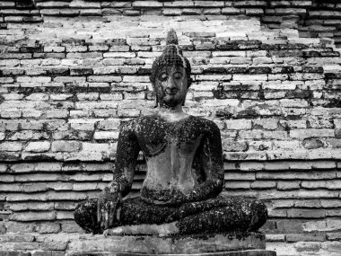Tayland 'daki UNESCO Dünya Mirası Bölgesi olan Sukhothai Tarihi Parkı' ndaki Wat Mahathat Tapınağı 'nda eski tuğla duvar arka planında eski bir Buda heykeli..
