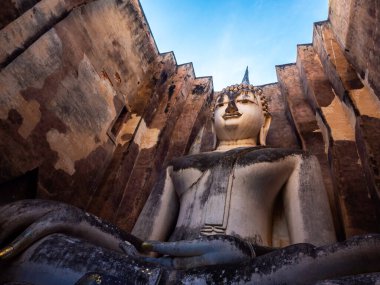 Wat Sri Chum Tapınağı 'nda mavi gökyüzü olan eski kilisenin içindeki antik büyük Buda heykeli Tayland' daki UNESCO Dünya Mirası Alanı Sukhothai Tarihi Parkı 'nda yer alıyor..