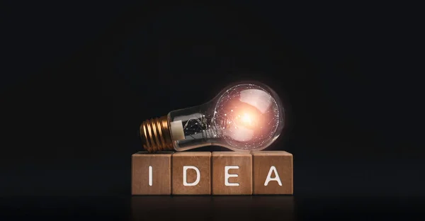 アイデア 暗い背景に輝く電球電気ランプと木製のキューブブロック上の言葉 創造的なアイデアのコンセプトバナー — ストック写真