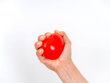 Kalp şeklindeki kırmızı bir stres topunu sıkmak, kalp sağlığını, kan basıncını, stres atımını, kardiyovasküler bakımı ve sağlık durumunu sembolize ediyor. Sağlıklı yaşam tarzı desteği kavramı.