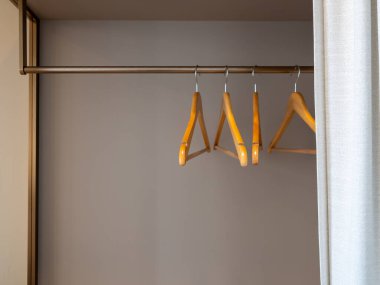 Wooden hangers in a hotel closet reflect guest room preparation, clothing storage service, and hospitality standards. Ideal for themes of travel, hotel service, and comfortable guest experience.