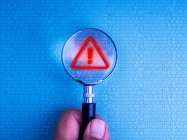 Bilgisayar ekranında elinde büyüteç olan ikili kod kırmızı uyarı sembolünü algılıyor. Siber güvenlik alarmı, dolandırıcılık tespit, veri ihlali, online tehdit izleme ve dijital risk kavramı.