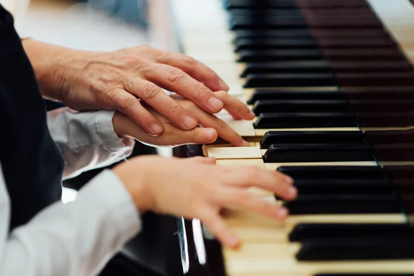 Mano experimentada de viejo maestro de música ayuda a alumno niño — Foto de Stock