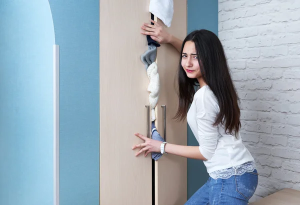 Dissatisfied girl trying to close  full wardrobe — Stock Photo, Image