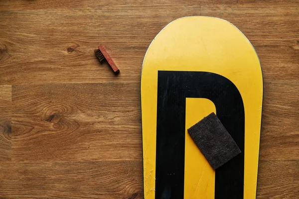 ahşap yerde yatarken sünger fırça ve snowboard balmumu,