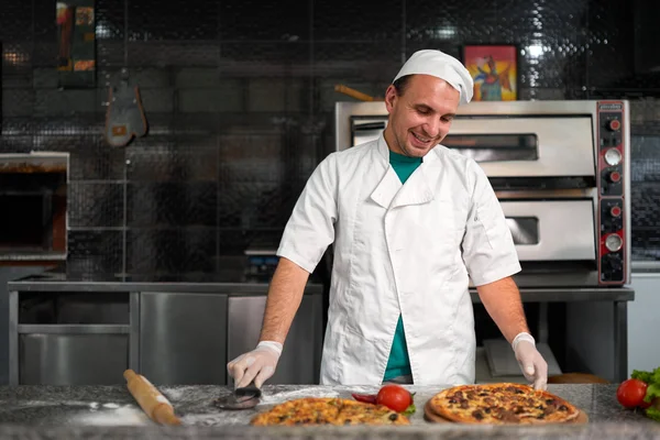 Koken aan tafel bereiden een verse pizza — Stockfoto