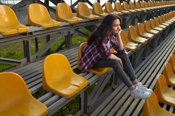 Beautiful lonely woman sitting on tribunes and smiles — Stock Photo, Image