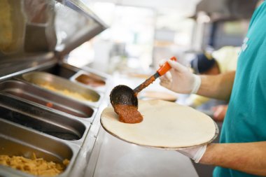 Şef pizza iş parçası domates sos koyar. Yakın çekim.