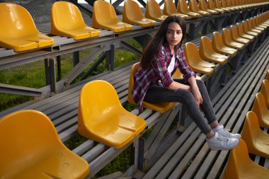 tribün ve bir kenara görünüyor üzerinde oturan güzel yalnız kadın.