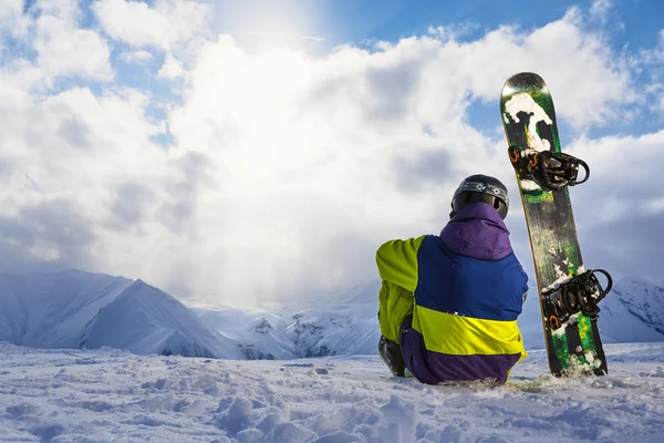 Snowboarder assis sur la neige et admirant le paysage hivernal . — Photo