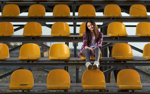 Lonely cheerleader girl sitting in stands and smiles sweetly. — Stock Photo, Image
