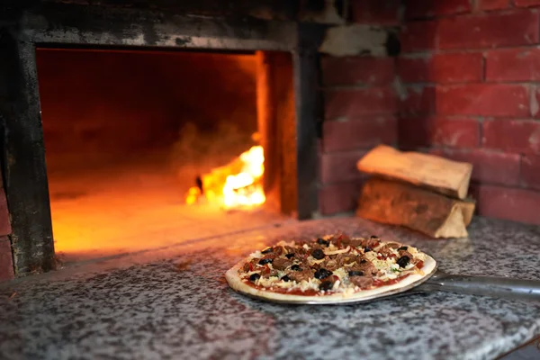 Pizza crua deitar fogão com o fogo na lâmina . — Fotografia de Stock