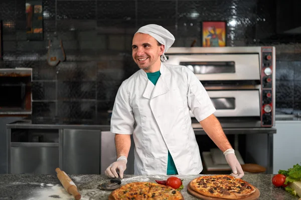 Koken aan tafel bereiden een verse pizza — Stockfoto
