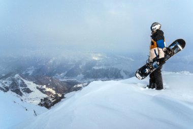 Dağlarda karlı havalarda cliff üzerinde duran snowboarder.