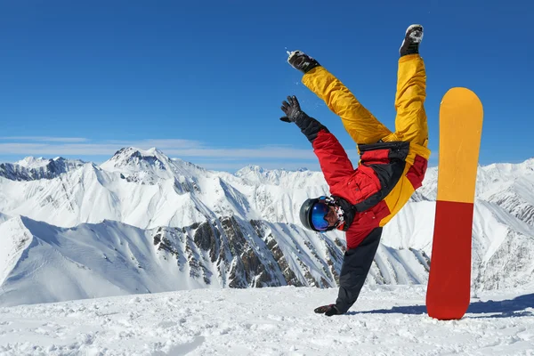 Hombre de pie en la mano al revés cerca de snowboard — Foto de Stock