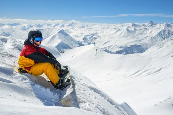 Snowboarder senta-se alto em montanhas na borda da encosta — Fotografia de Stock