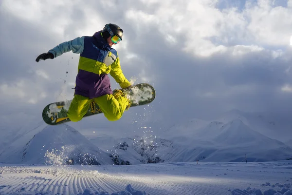 Snowboarder doet de springen truc. sneeuw verstrooit stukken — Stockfoto