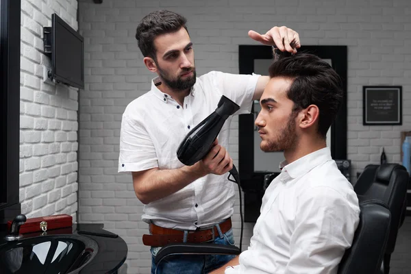 プロのヘアスタイリストがクライアントのドライヤーで髪を乾燥します。 — ストック写真