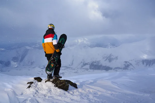 Snowboarder steht auf einem Felsen an der Steilküste — Stockfoto