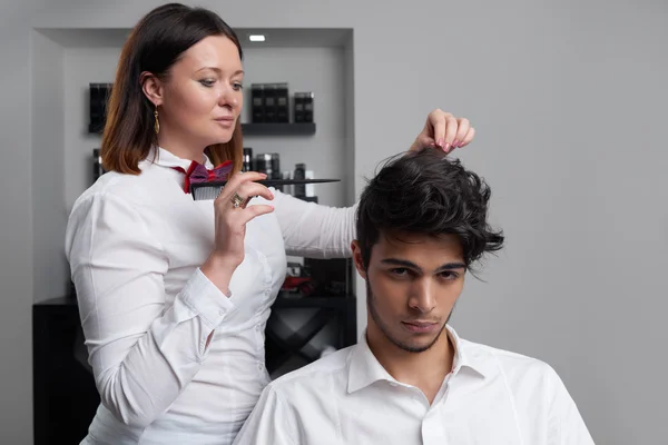Профессиональный парикмахер расчесывает волосы клиента щеткой — стоковое фото