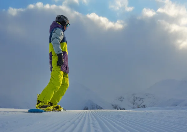 Snowboarder de pé sobre a placa nas montanhas — Fotografia de Stock