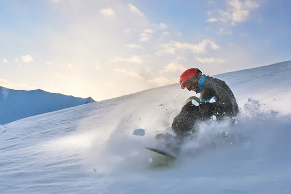 Meisje snowboarder vertraagt de helling op achtergrond van zonsondergang — Stockfoto