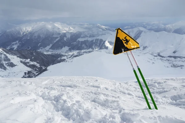 Etiqueta aviso de um penhasco afiado, de pé em montanhas nevadas . — Fotografia de Stock