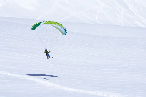 Groene skiër eindigen met een paraglider — Stockfoto