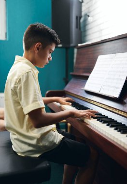 Çocuk müzik dersinde piyano çalıyor.