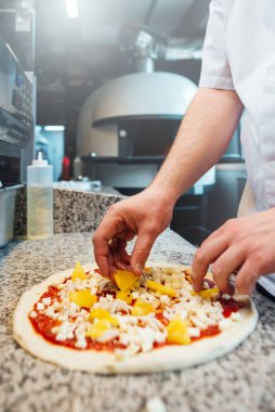 Şef pizzaya peynir koyar. Mutfak işleri..