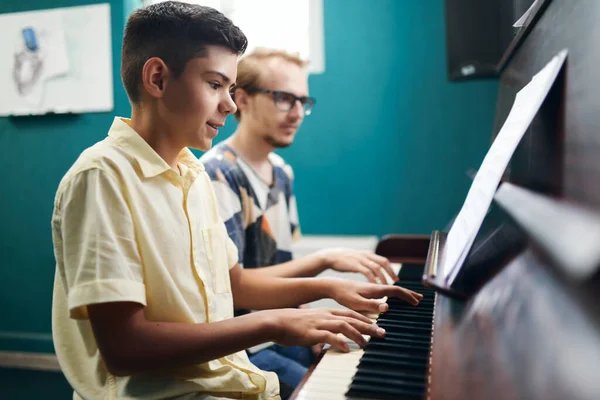 Leende pojke spelar piano med sin lärare — Stockfoto