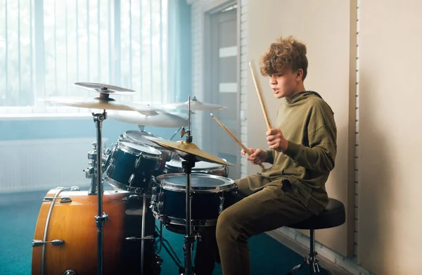 Młody blondynka nastolatek chłopiec grać perkusja zestaw w studio. — Zdjęcie stockowe