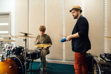 Çocuk davul çalışıyor. Öğretmenle müzik okulu dersi..