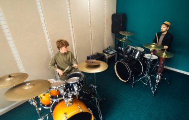 Çocuk davul çalışıyor. Öğretmenle müzik dersi..