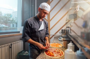 Aşçı malzemeleri pizza hamuruna koyar. Mutfak işleri..