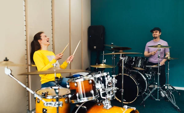 Το κορίτσι πίσω από το drum kit γελάει. Μάθημα μουσικής με δάσκαλο. — Φωτογραφία Αρχείου