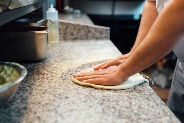 Kocken knådar pizzabudden på bordet. Köksarbete. — Stockfoto