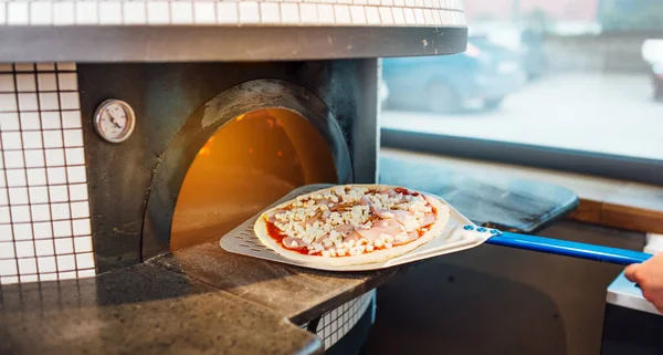 Il cuoco mette la pizza sulla spatola in forno. Lavori di ristorazione cucina. — Foto Stock