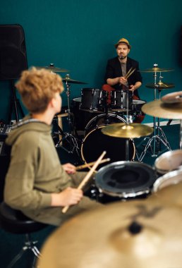 Öğretmen çocuğa nasıl davul çalınacağını doğru şekilde gösterir. Müzik okulunda ders..