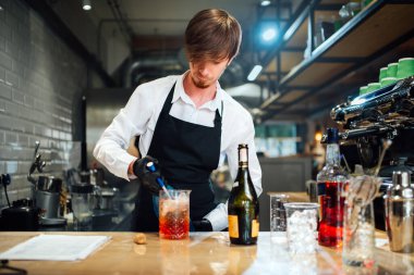 Barmen içki malzemelerini karıştırma kabına içki makinesi kullanarak doldurur. Kokteyl hazırlama süreci