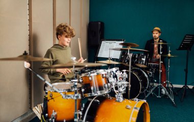 Çocuk davul seti çalıyor. Öğretmenle müzik dersi..