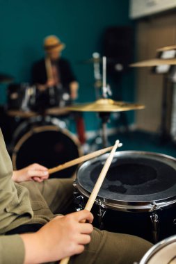 Erkeklerin elinde bagetler. Müzik okulunda davul dersi..