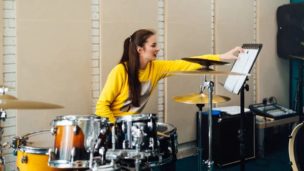 Jovem mulher lançando notas para a bateria. Lição na escola de música de bateria. — Fotografia de Stock