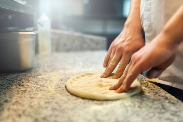 Szef kuchni ugniata ciasto na pizzę palcami. Kuchnia cateringowa. — Zdjęcie stockowe