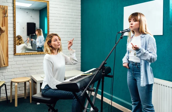 Vocal teacher showing her student how to sing — Stock Photo, Image