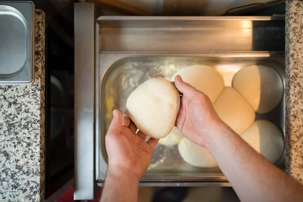 Szef kuchni bierze czystą pizzę z blachy do pieczenia w szufladzie lodówki rękami.. — Zdjęcie stockowe