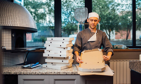Pizzeria worker building pizza box. Catering kitchen work.