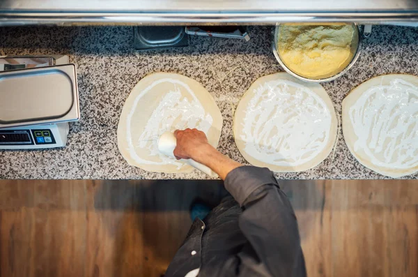 Kocken klämmer sås på pizzabudden. Köksarbete. — Stockfoto