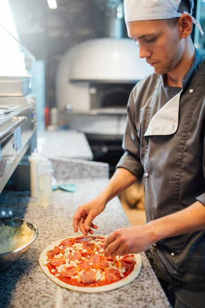 Chef maakt pizza. Keukenwerk voor catering. — Stockfoto
